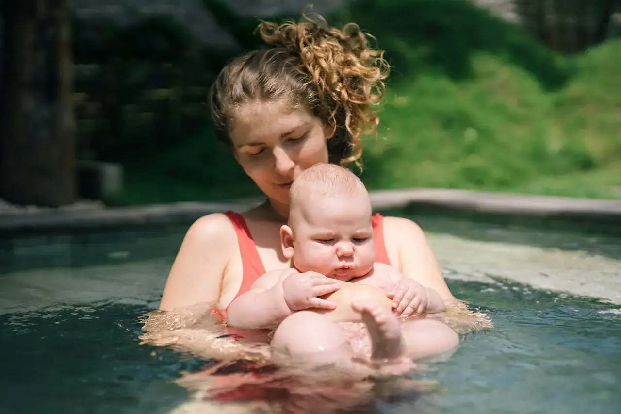 Mutter hält ihr Baby behutsam im warmen Wasser